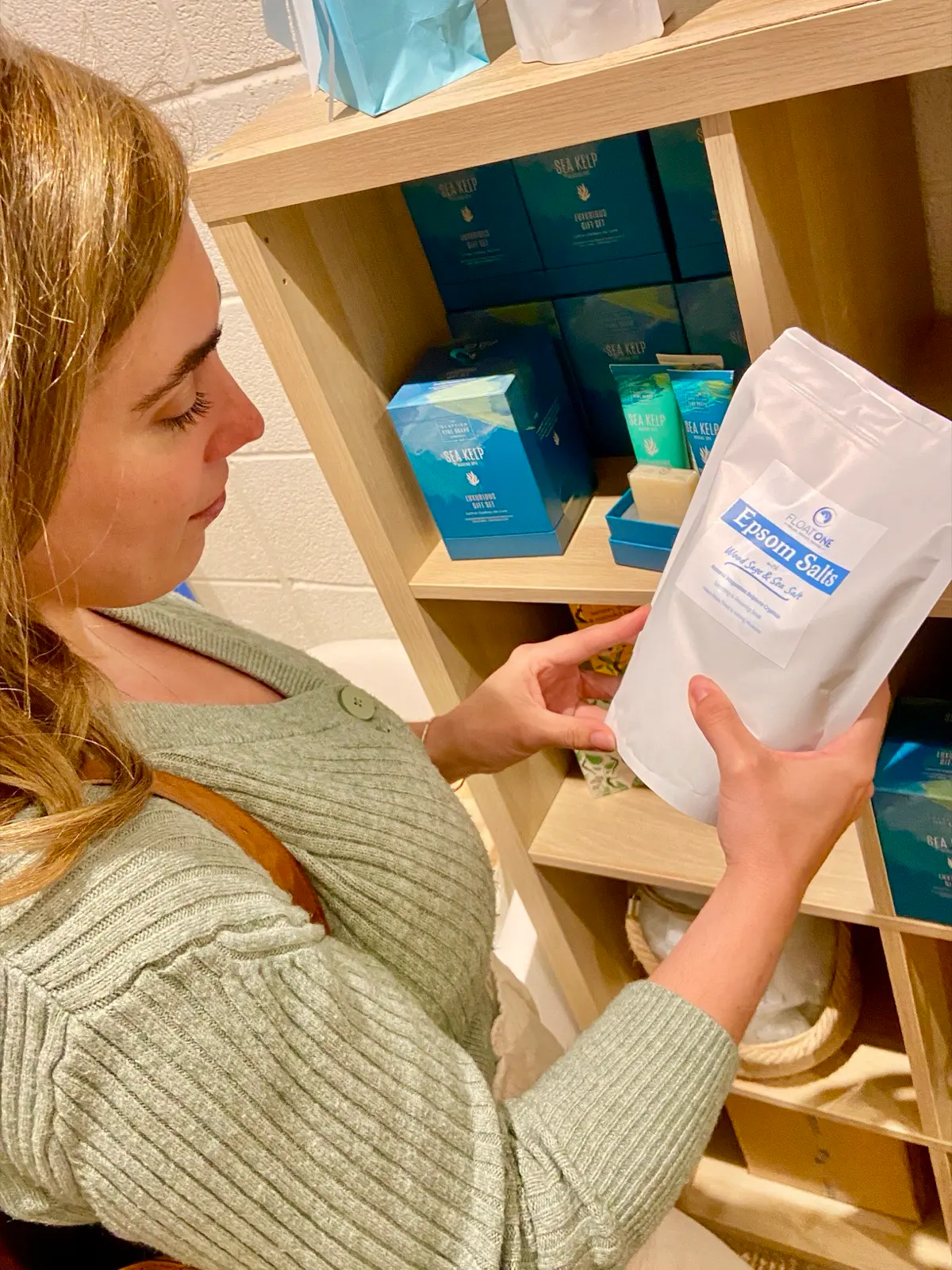 Guest exploring Epsom salts and aftercare products after her FLOAT ONE session