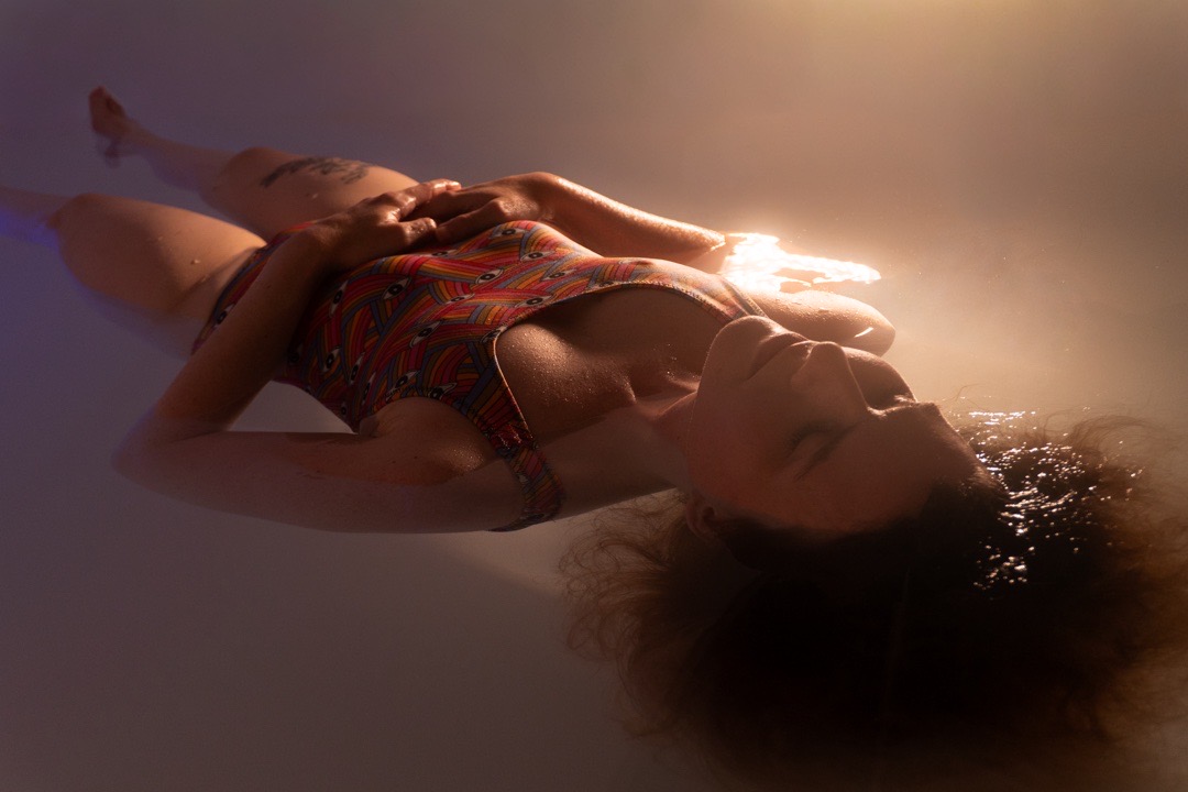 FLOAT ONE guest resting in float water under soft warm light