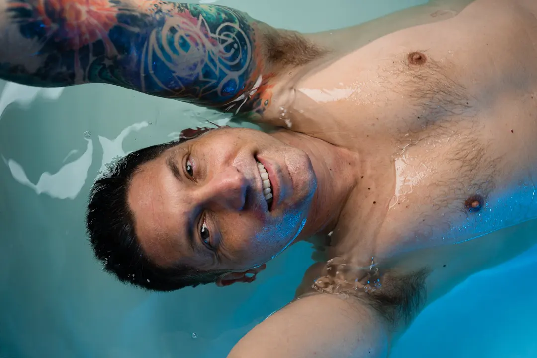 A FLOAT ONE guest smiling while floating in blue-lit water