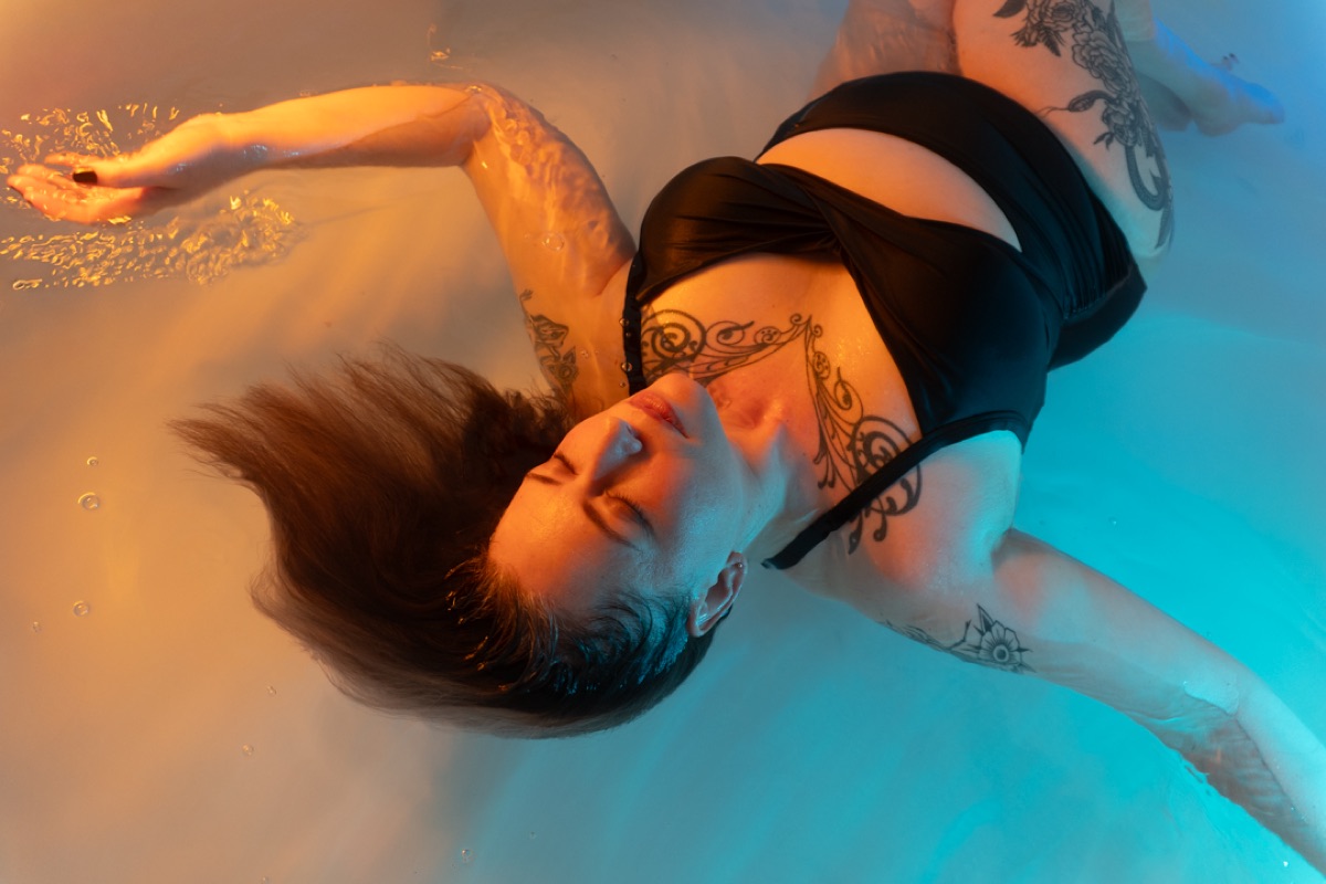 Tattooed FLOAT ONE guest floating under warm and blue light